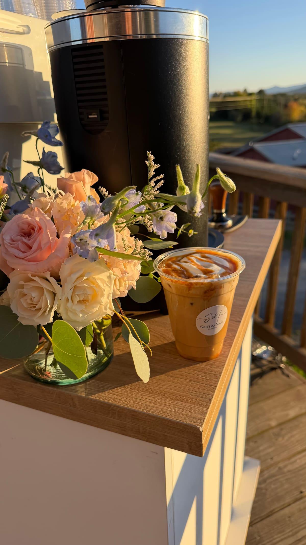 Pink and white roses and an iced latte on the cart’s wooden counter, on a deck in the evening sun