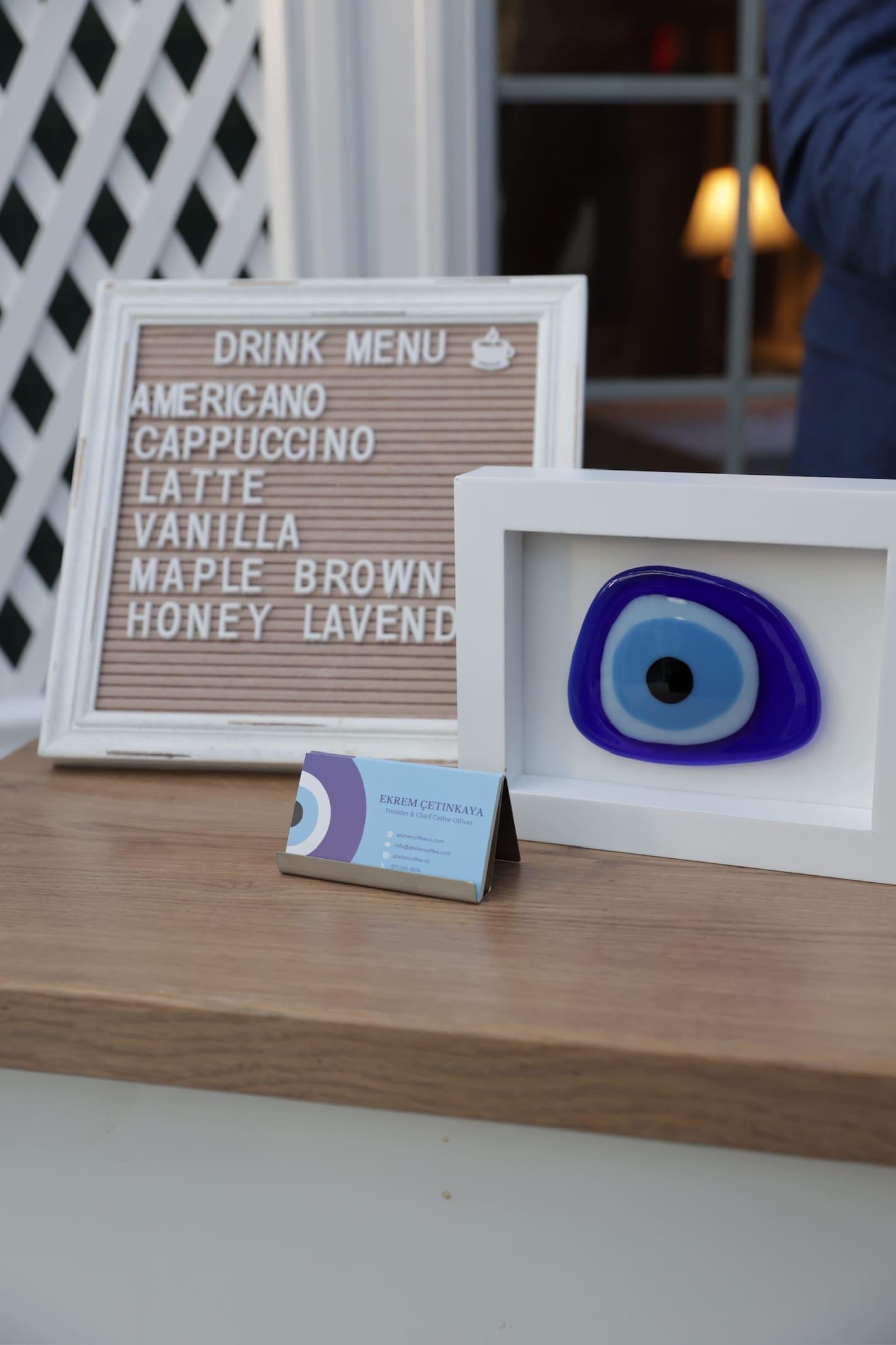 A letter board drinks menu beside the blue nazar on the cart’s counter