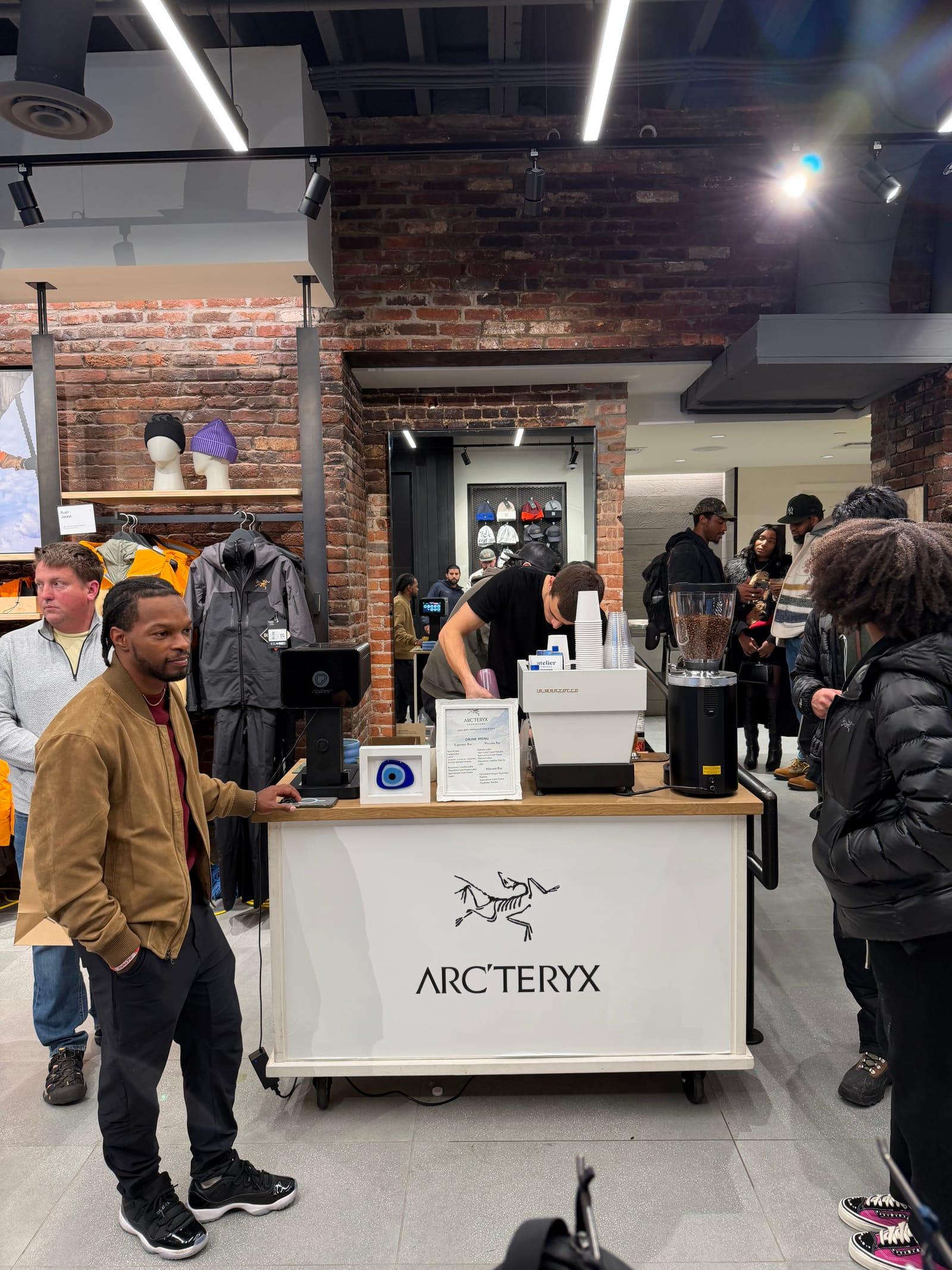 Guests gathered around an Arc’teryx branded espresso cart inside the store