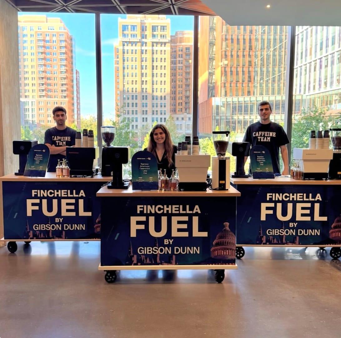 Atelier baristas behind three espresso carts wrapped in a sponsor’s branding