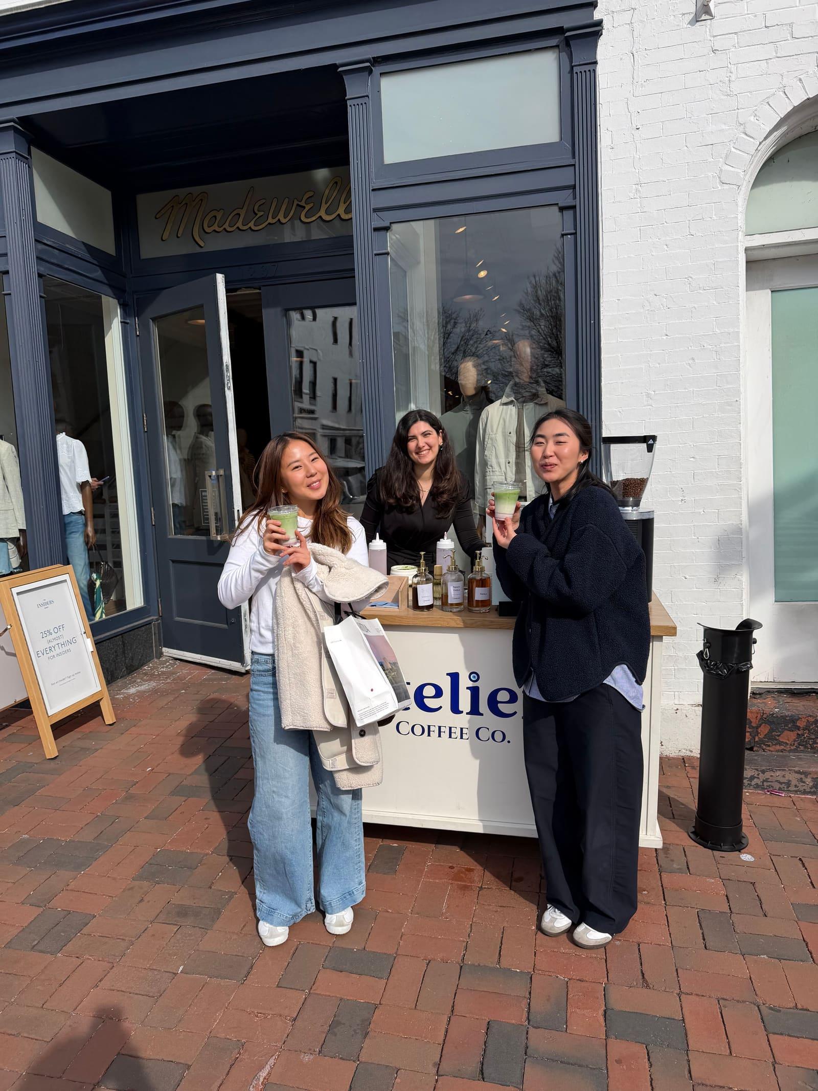 Three guests with drinks in hand at the Atelier cart outside a Madewell storefront