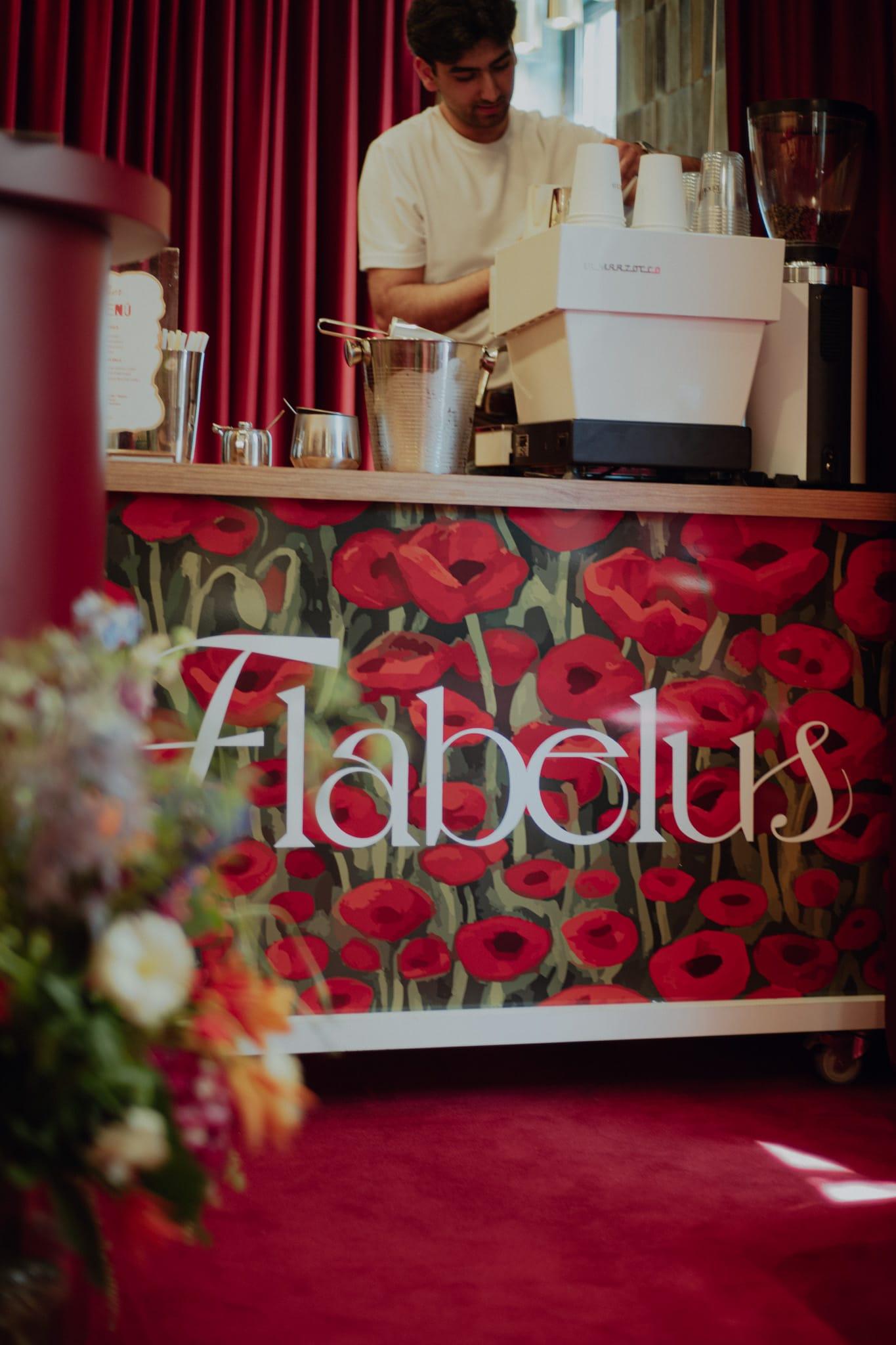 A barista at an espresso cart wrapped in red poppy artwork